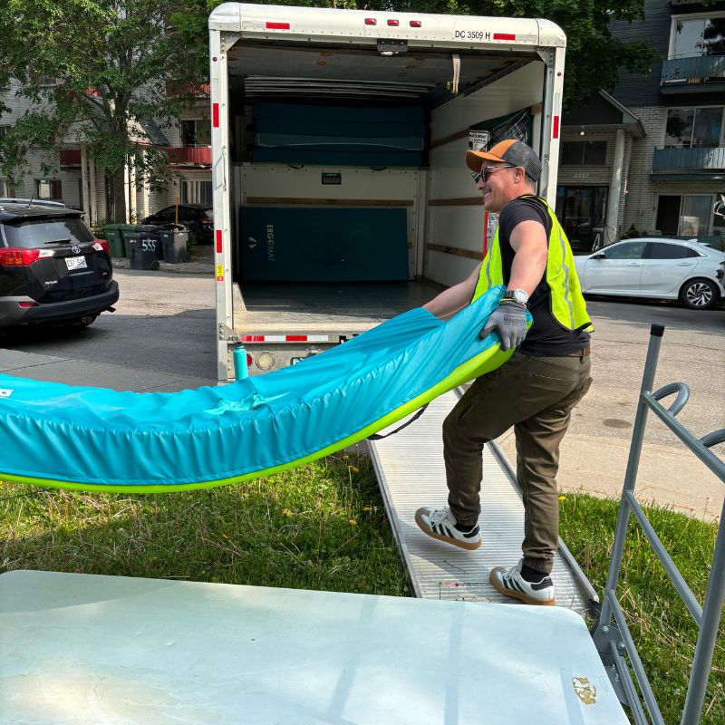 Employé montant un matelas bleu dans un camion de recyclage