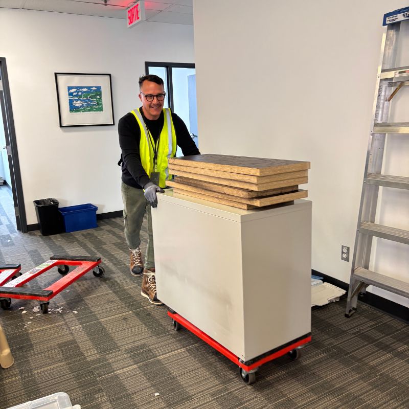 Employé poussant un caisson de bureau blanc avec des plateaux en bois