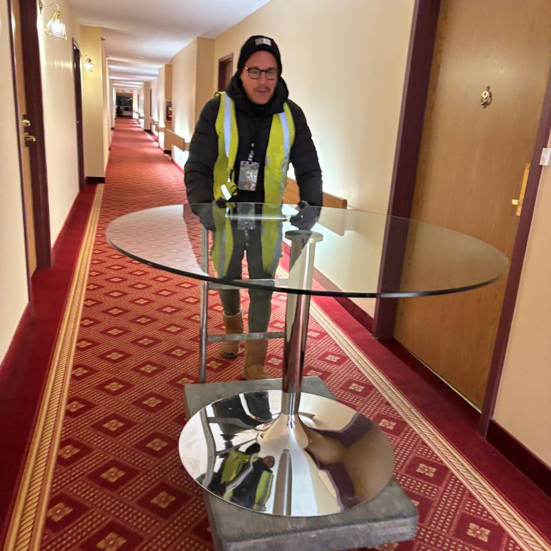 Transport d’une table ronde en verre dans un couloir d’hôtel